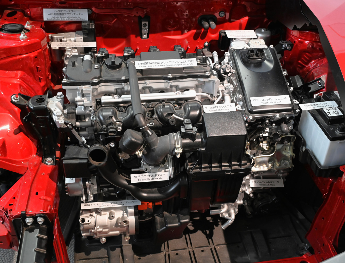 Figura H7. Model secționat Toyota Prius ZVW50 expus. Fotografia arată amplasarea motorului termic și a echipamentelor electrice hibride, nu schema completă a fluxurilor de putere. Foto: TTTNIS, Wikimedia Commons, CC0 1.0. Vezi atribuirea imaginilor.