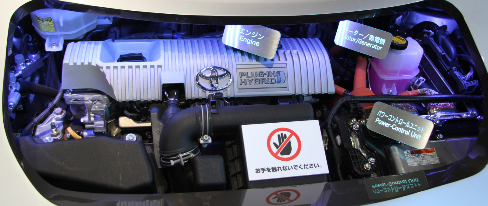 Studiu fotografic. Compartiment motor Prius PHV dintr-o generație anterioară, fotografiat în 2013. Hardware-ul termic convențional și electronica hibridă coexistă; funcțiile trebuie diferențiate, fără a atribui defectul numai categoriei vehiculului. Foto: TTTNIS, Wikimedia Commons, Public domain dedication. Vezi atribuirea imaginilor.